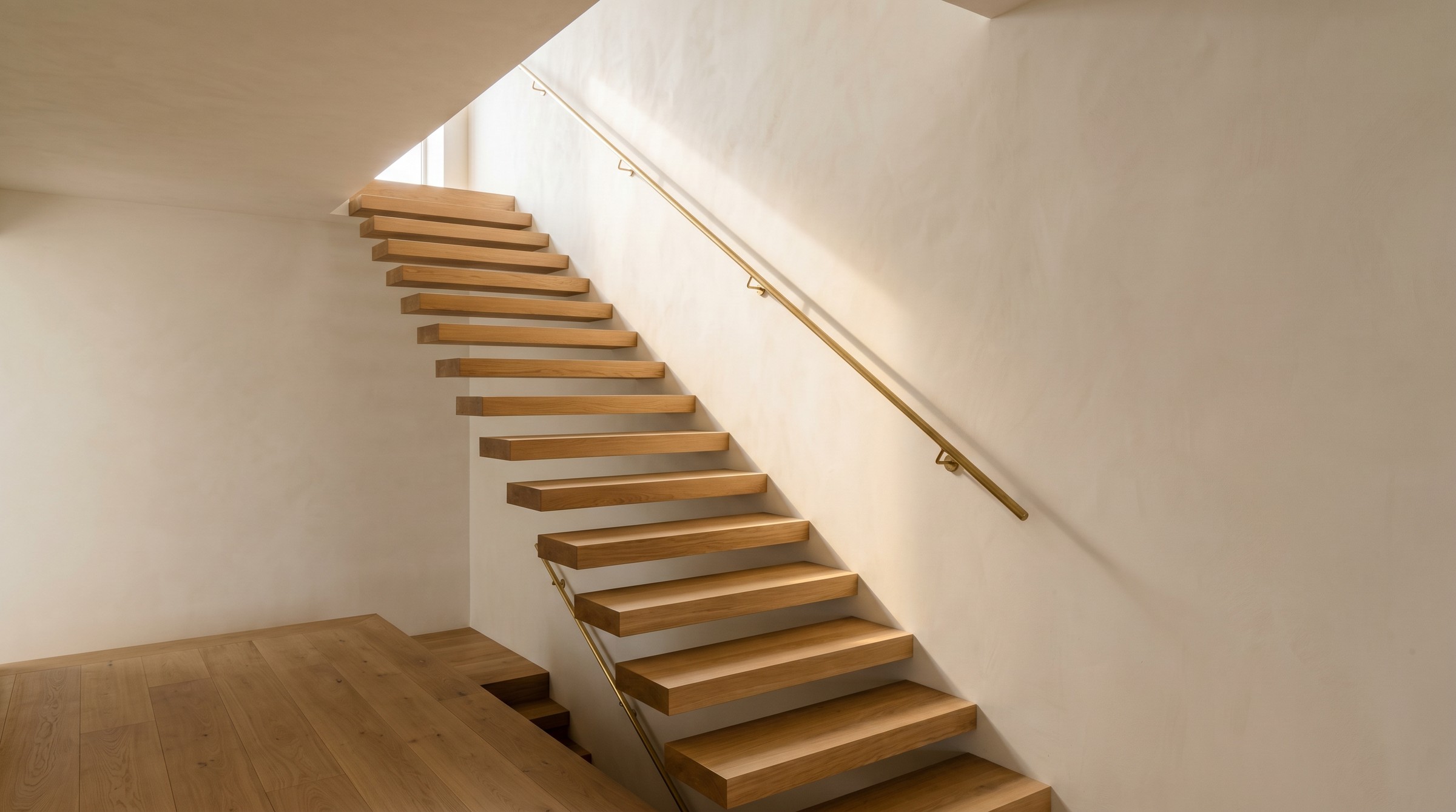 Architectural still — light falling across a lime-plaster wall, oak stair treads cantilevered into shadow